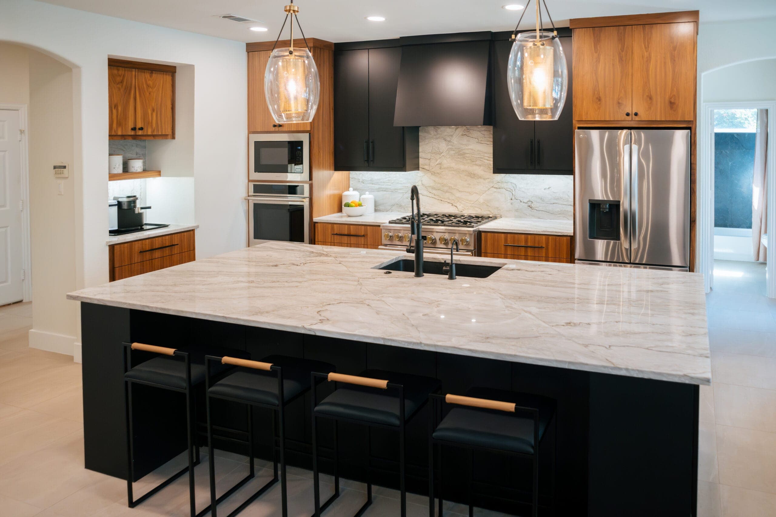 Marble-look waterfall island with bar seating under glass lantern pendants