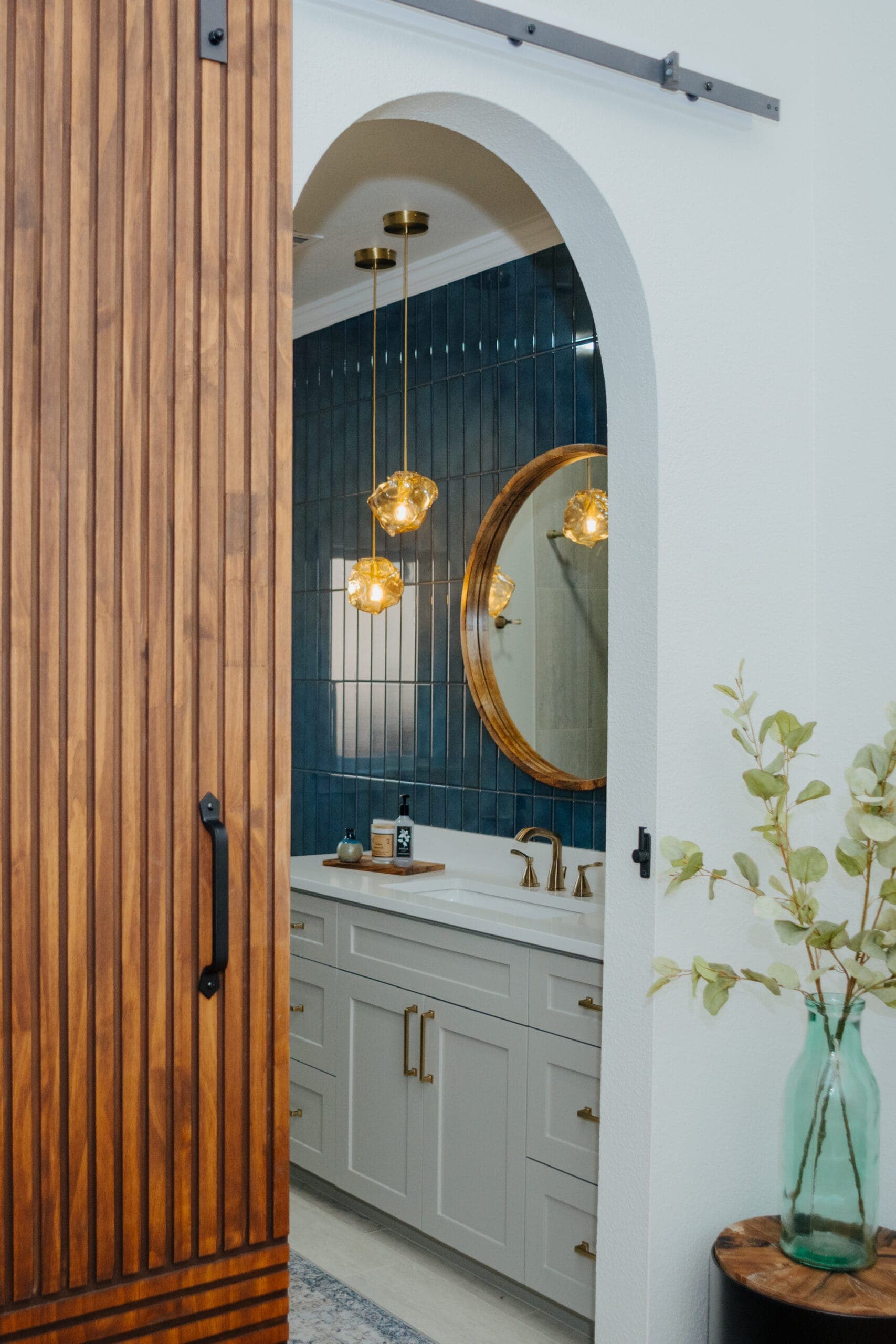Arched doorway framing a bathroom with a blue vertical tile accent wall