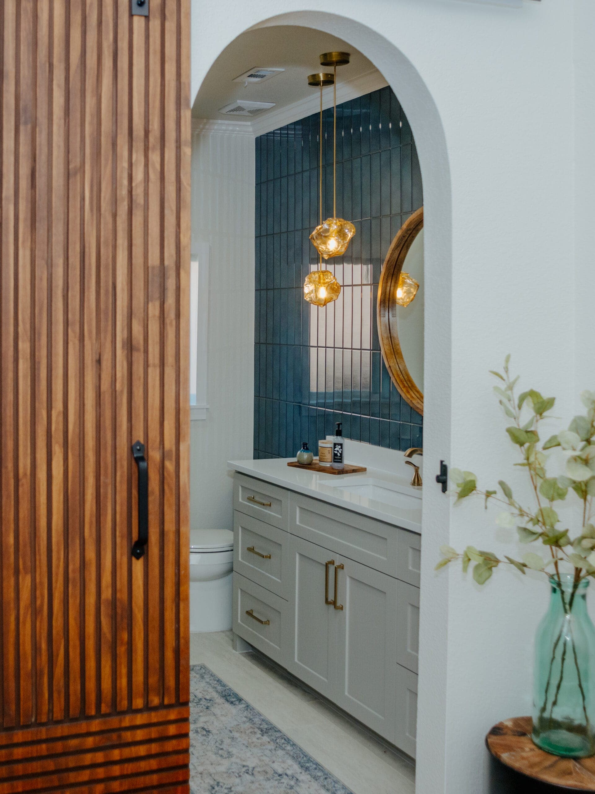 View through an arched entry past a wood slat door to the remodeled vanity
