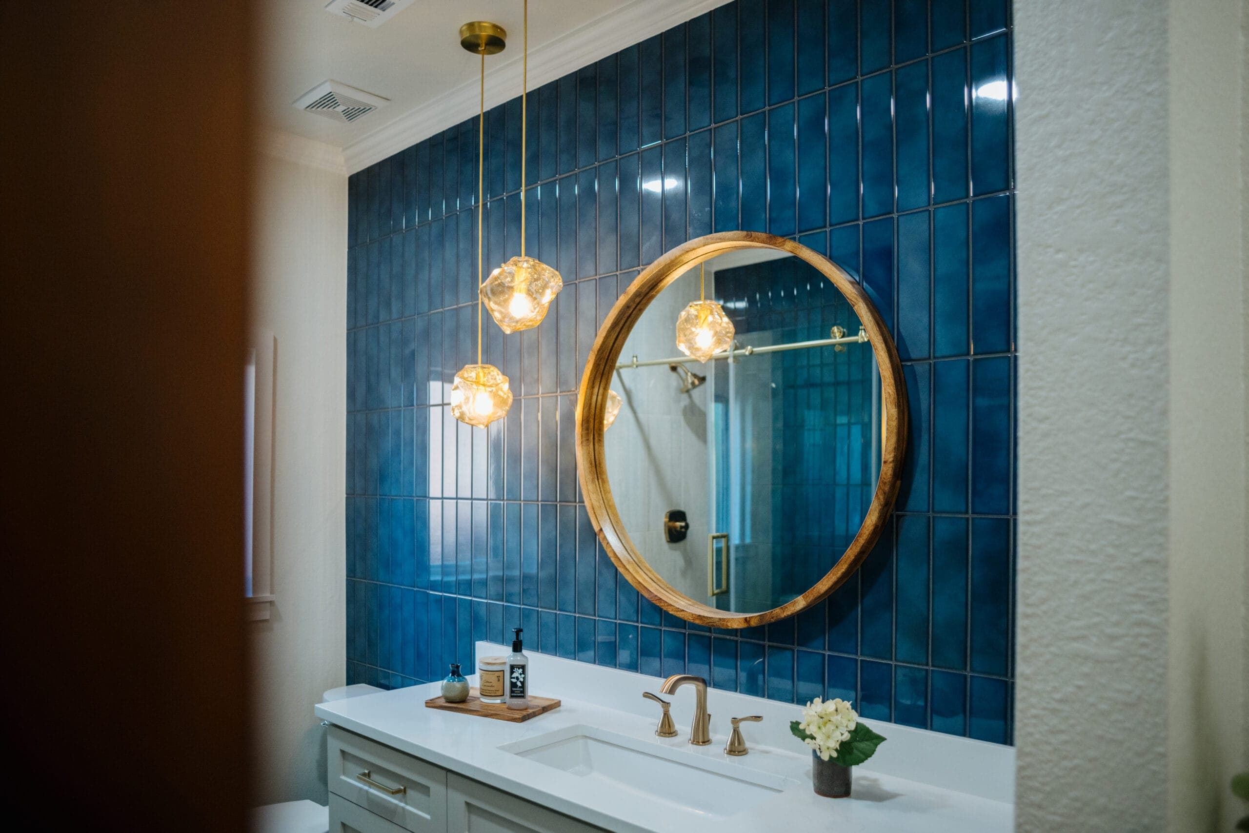 Blue tile accent wall lit by two glass globe pendants above the vanity