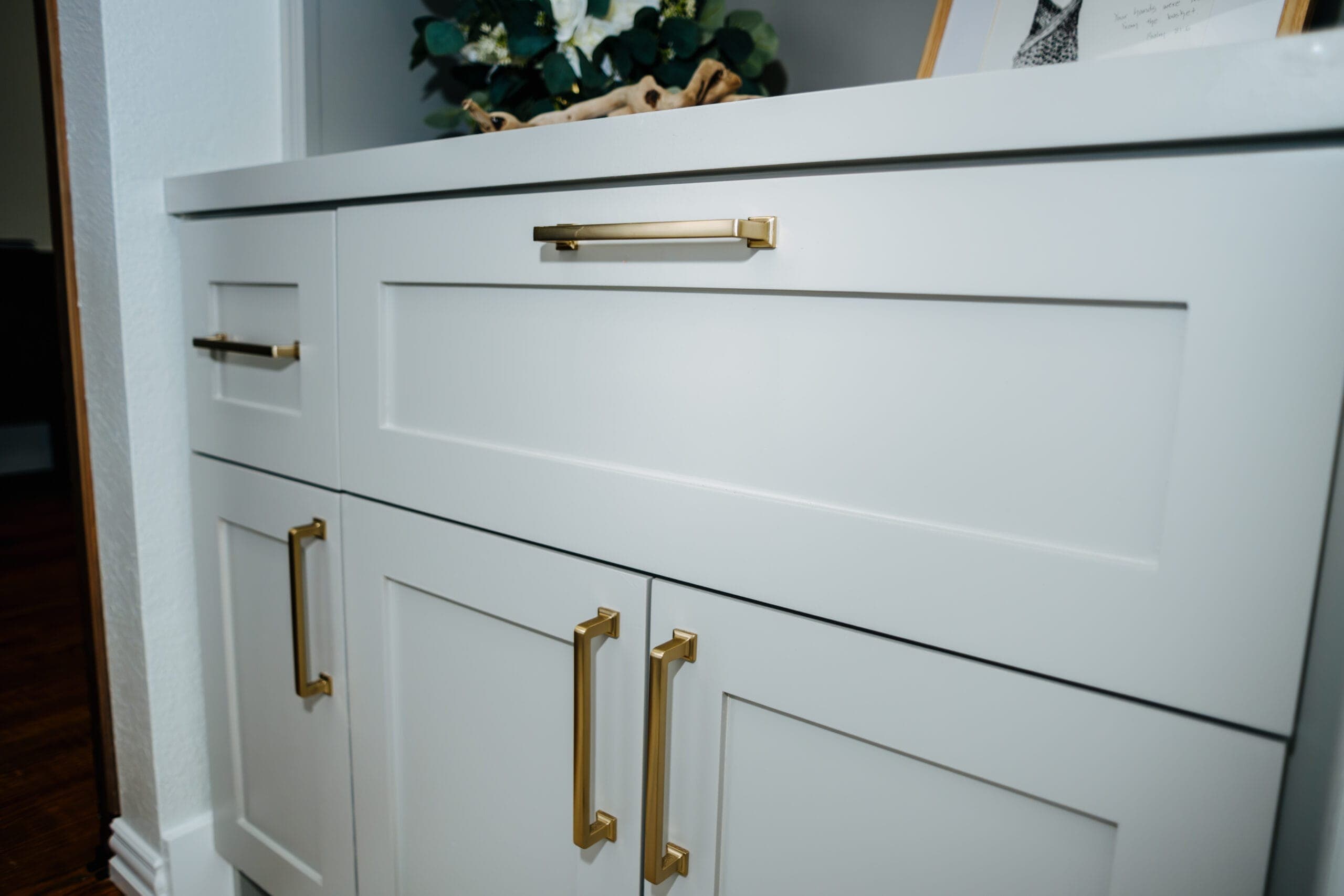 Detail of a white shaker vanity with brass bar and knob hardware