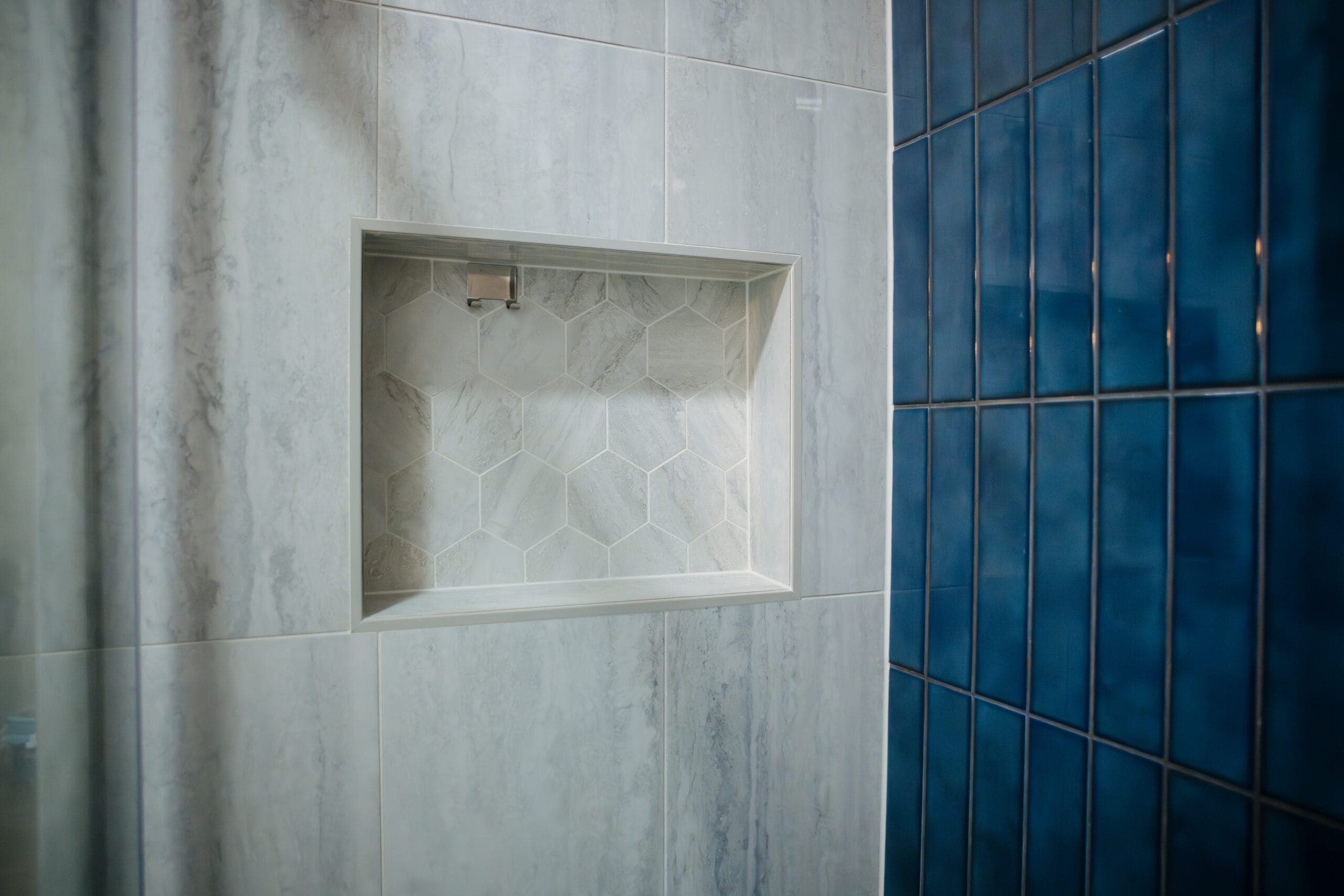 Recessed shower niche set into large-format marble-look tile