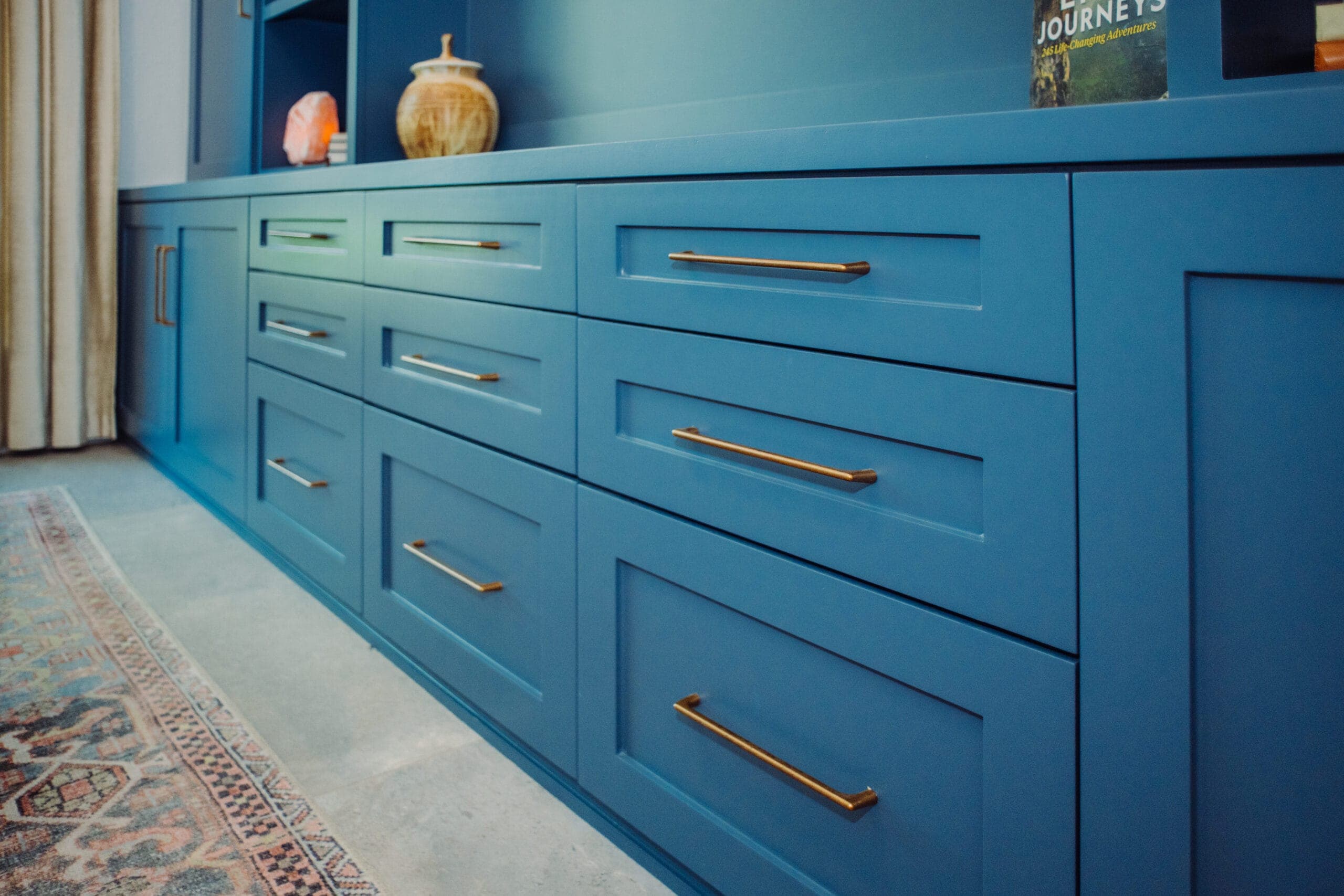 Run of blue built-in drawers with long brass pulls