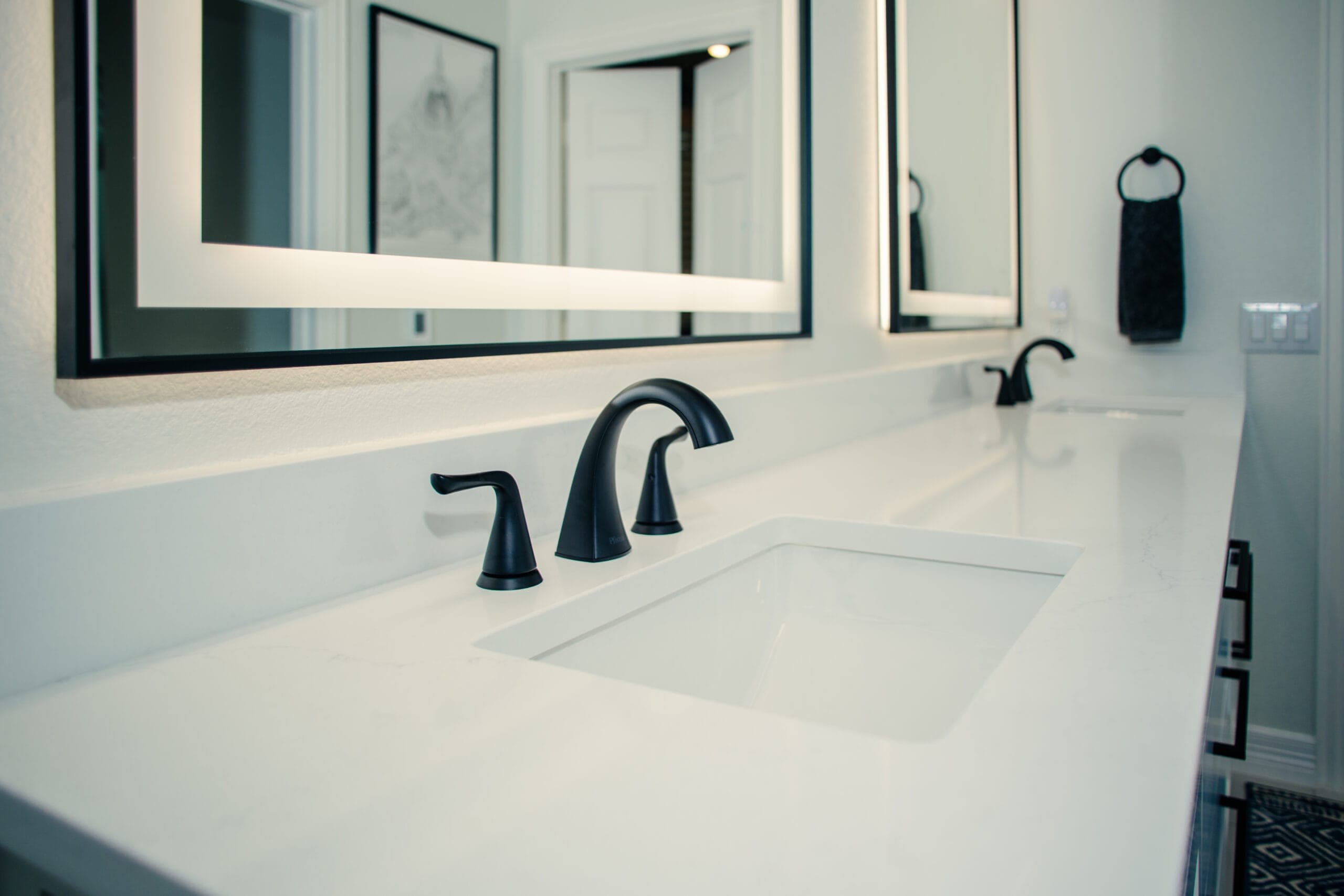 Dual undermount sinks on a continuous white quartz counter with black fixtures