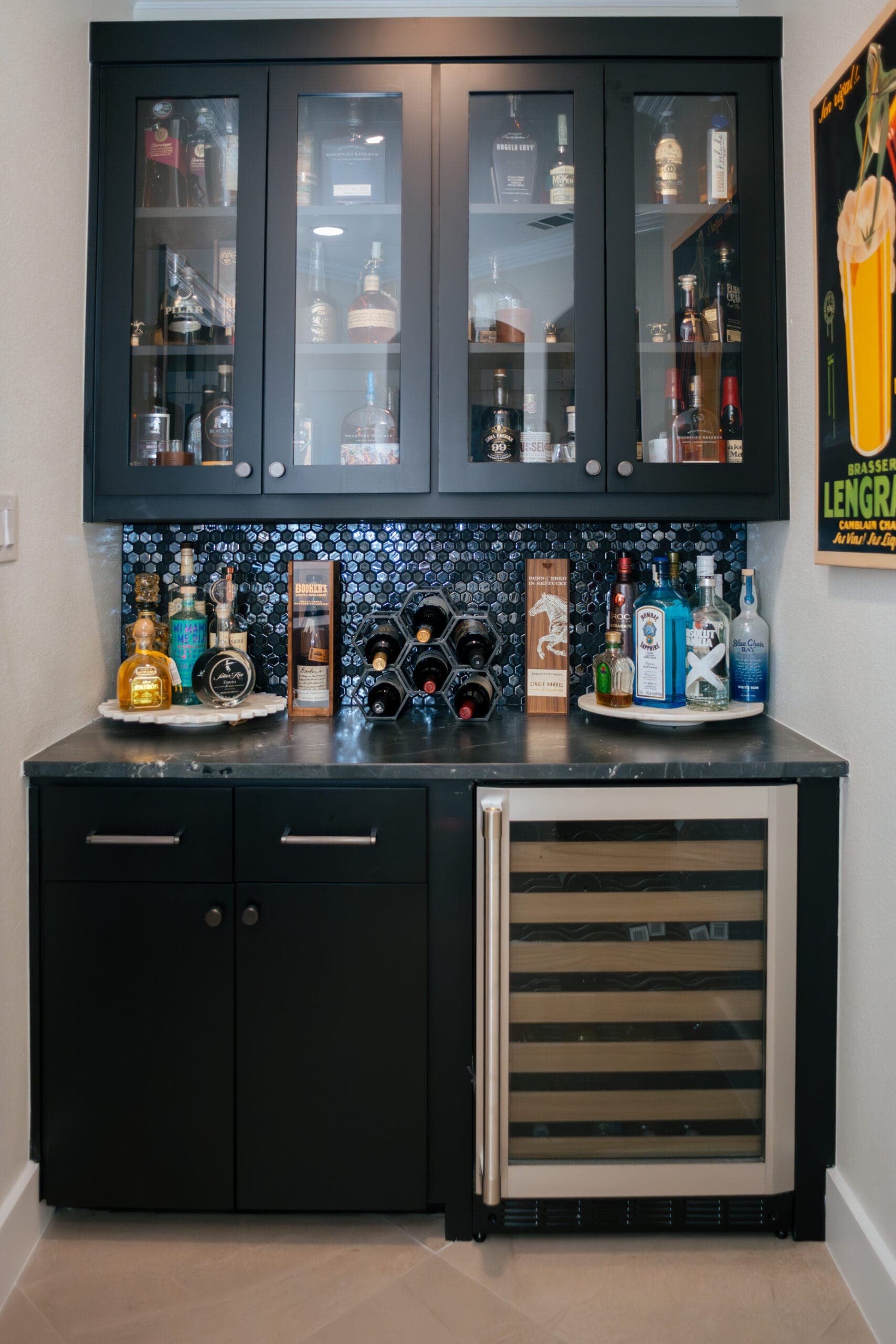 Wet bar with black glass-front cabinets, blue mosaic backsplash and an undercounter wine refrigerator