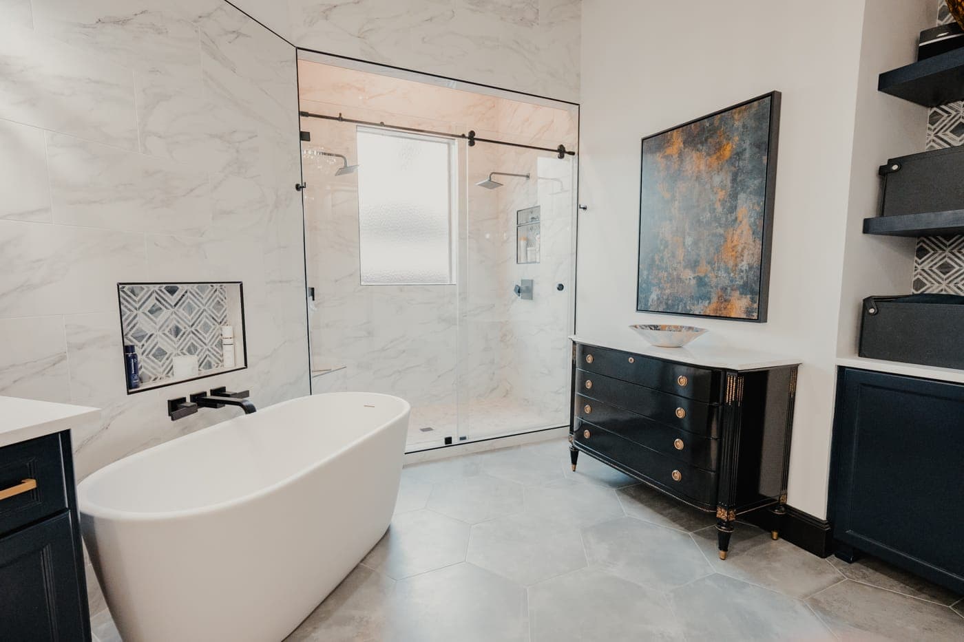 Freestanding tub beside a frameless glass shower in a marble-clad primary bathroom