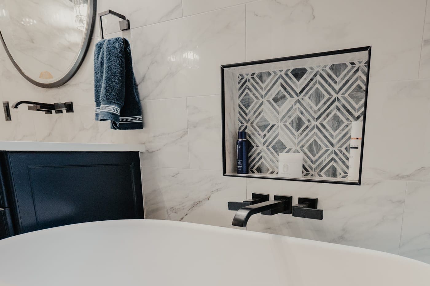 Freestanding tub with a matte black wall-mount filler and a patterned tile inset