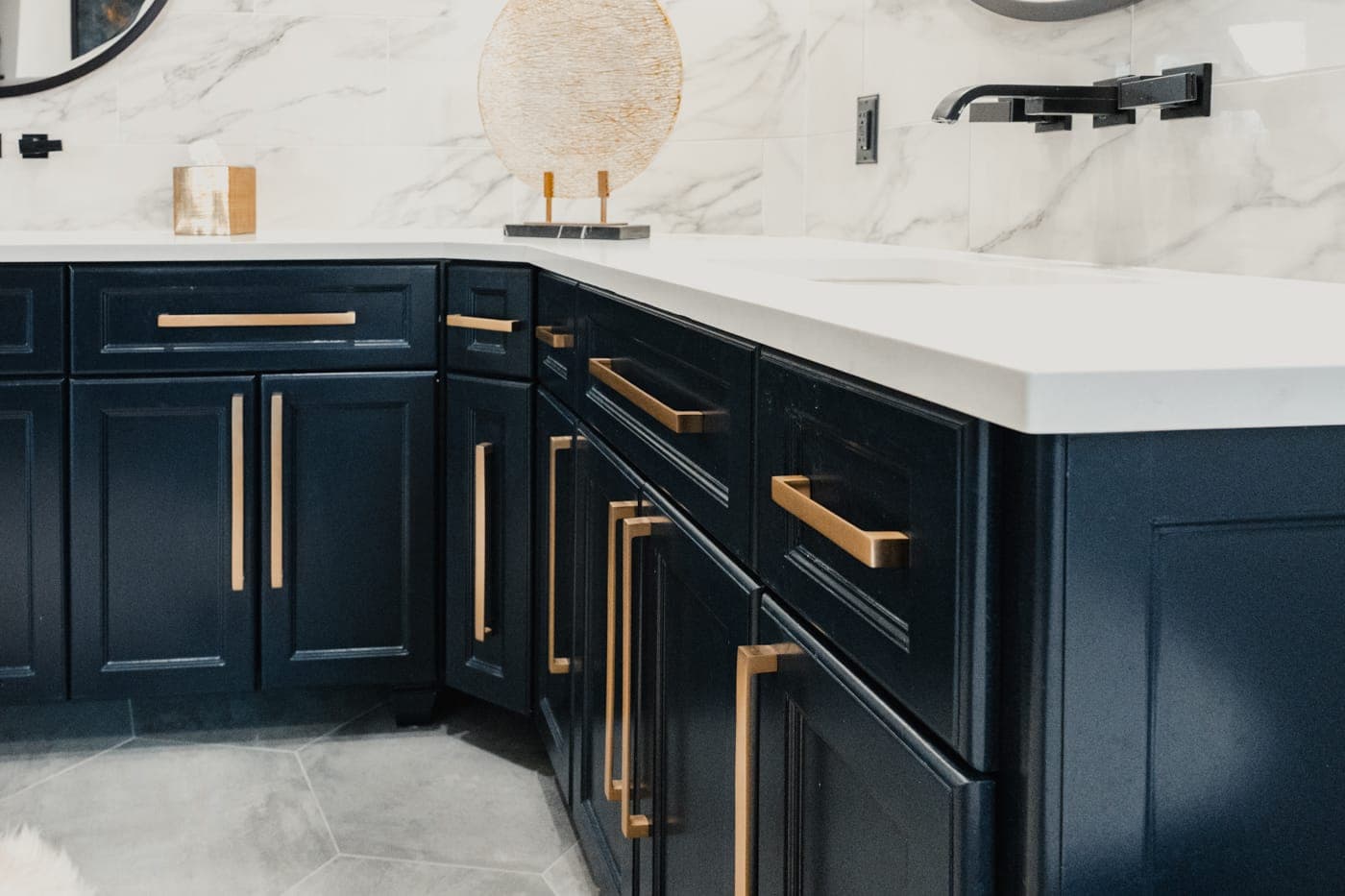 Navy cabinet fronts with elongated brass hardware below a white quartz counter