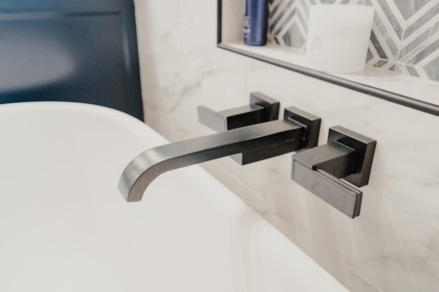 Close view of a squared wall-mount tub filler above a freestanding tub