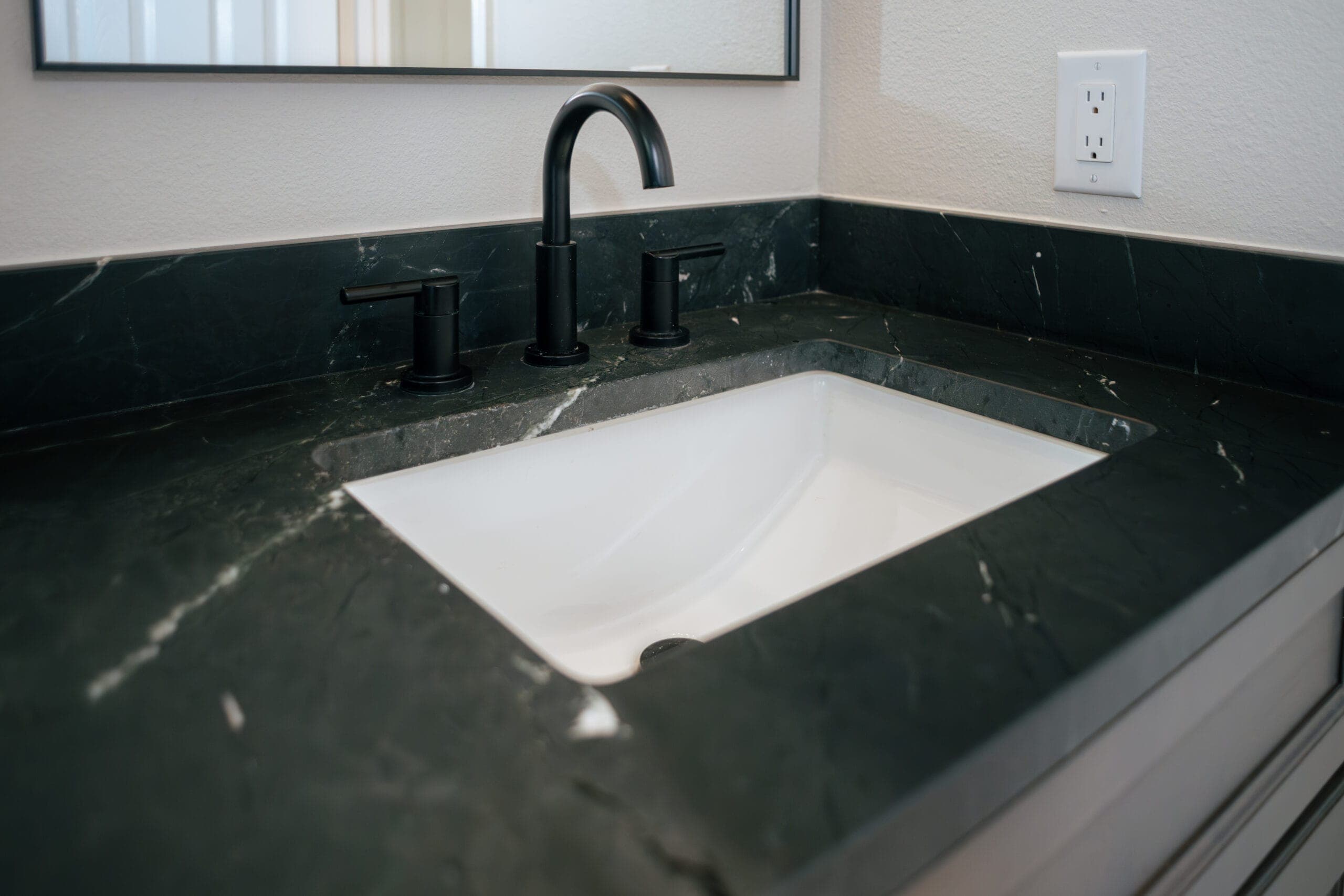 Dark stone vanity top with an undermount sink and matte black faucet