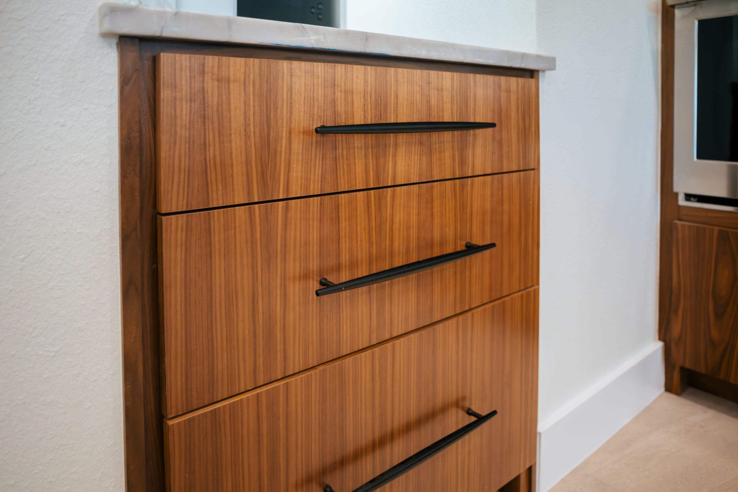 Stack of walnut flat-panel drawers with long black bar pulls