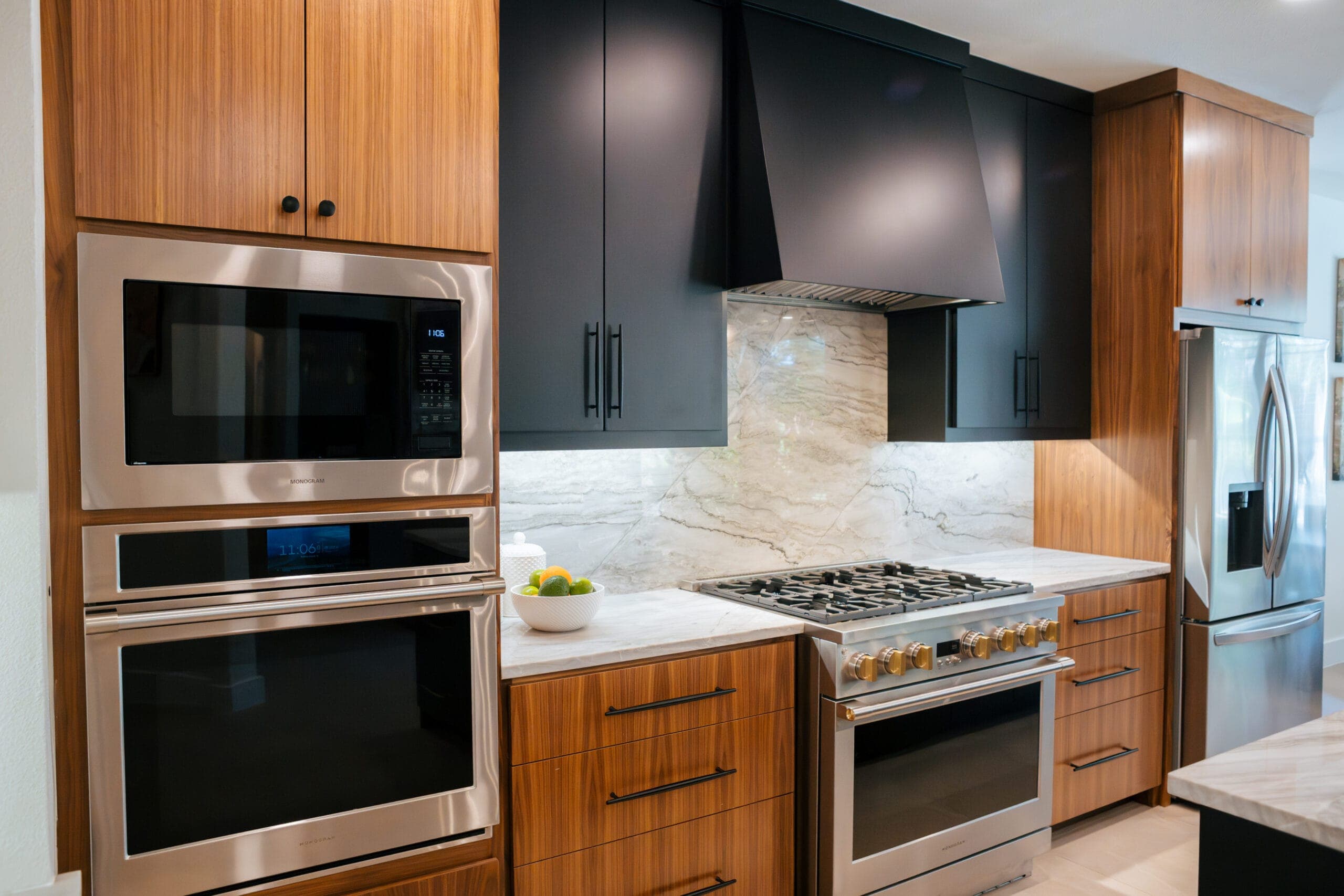 Two-tone range wall with walnut base cabinets, black uppers and a stone backsplash — kitchen remodeling by Southlake Luxury Kitchens, serving Southlake, TX