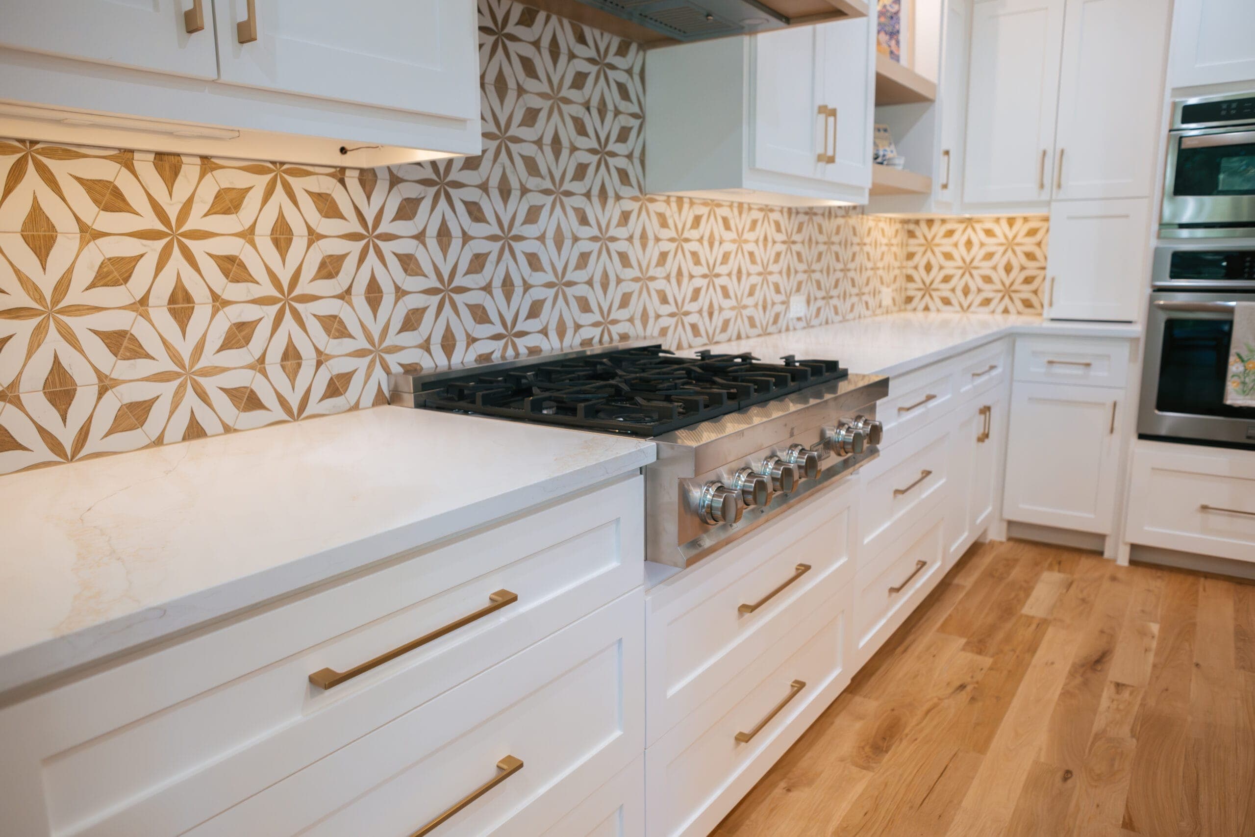 Quartz counter run with deep drawer storage below a gas rangetop and tile backsplash