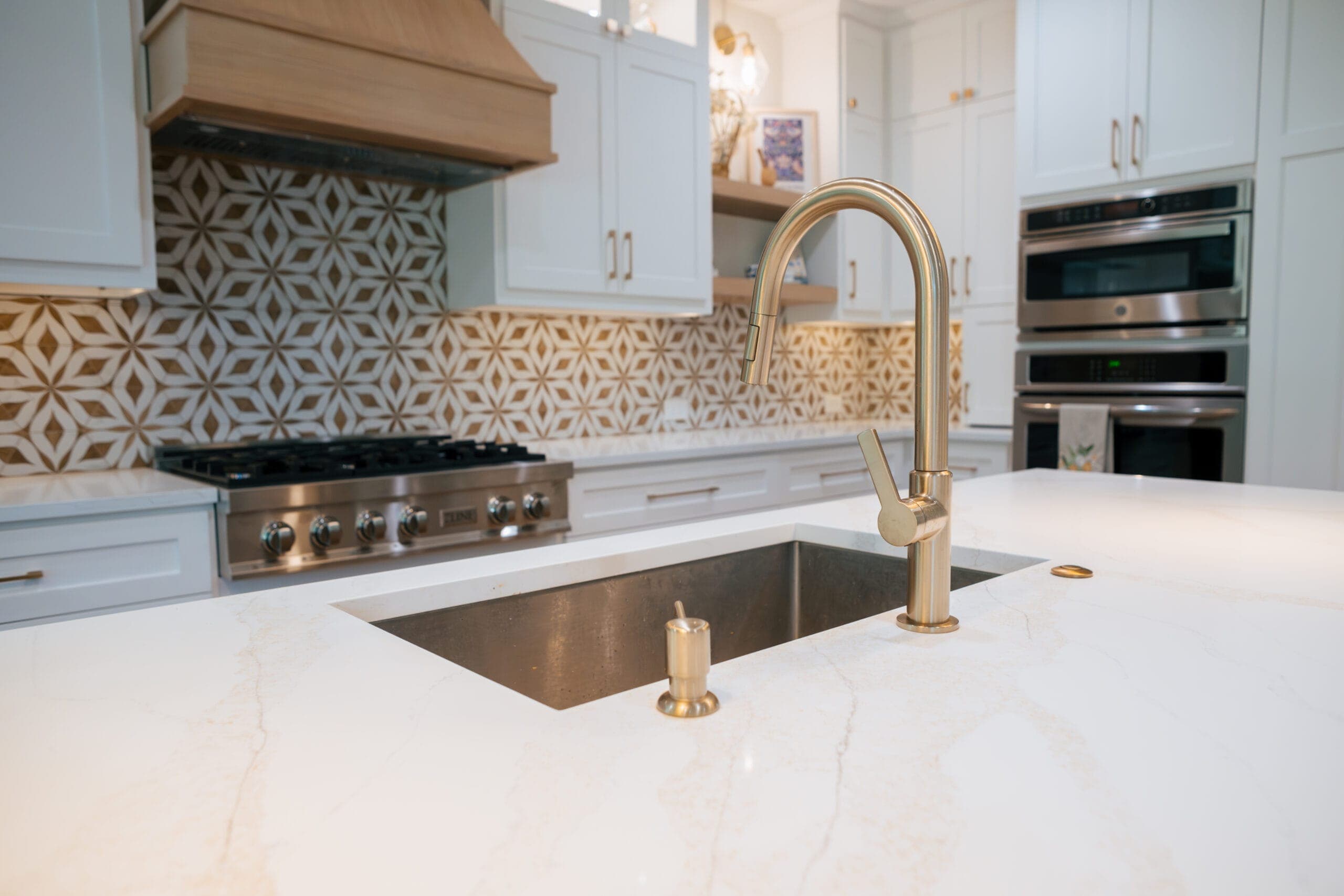 Undermount sink and brushed brass gooseneck faucet set into a quartz island counter