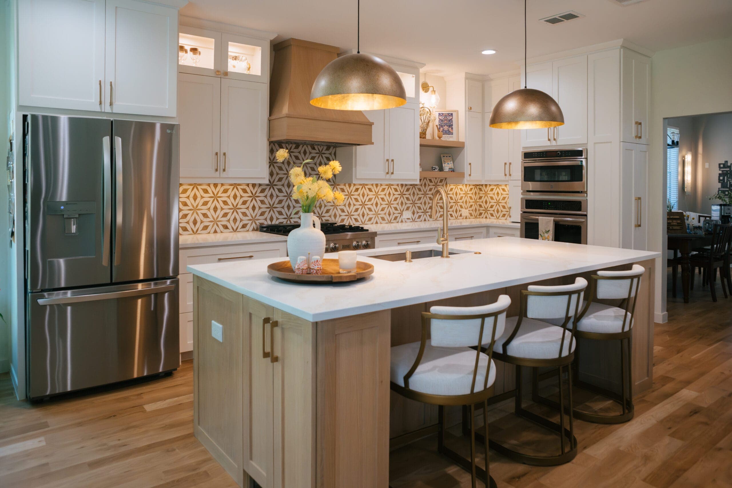 White oak island with counter stools and brushed brass dome pendants in an open-plan kitchen remodel by Southlake Luxury Kitchens, serving Southlake, TX