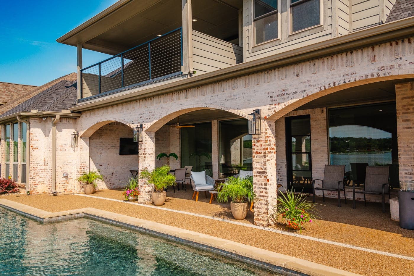 Covered patio with brick arches overlooking a pool after a whole-house renovation