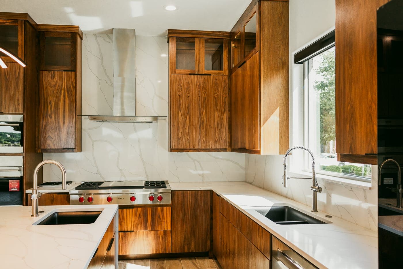L-shaped walnut kitchen with double sinks, stone counters and a window over the prep area