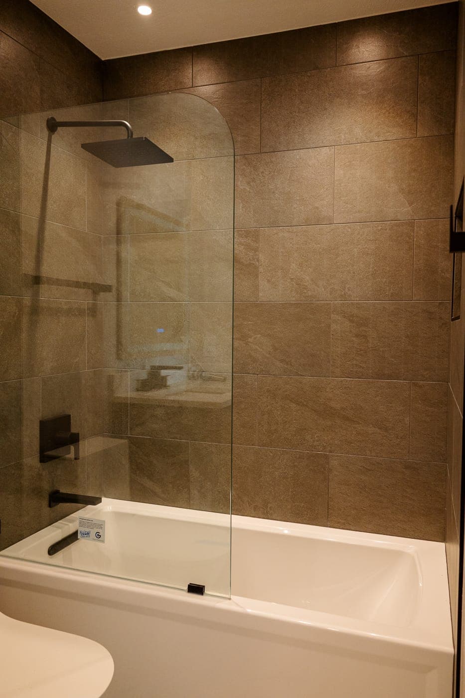 Tub and shower combination with a fixed glass panel and large-format tile surround